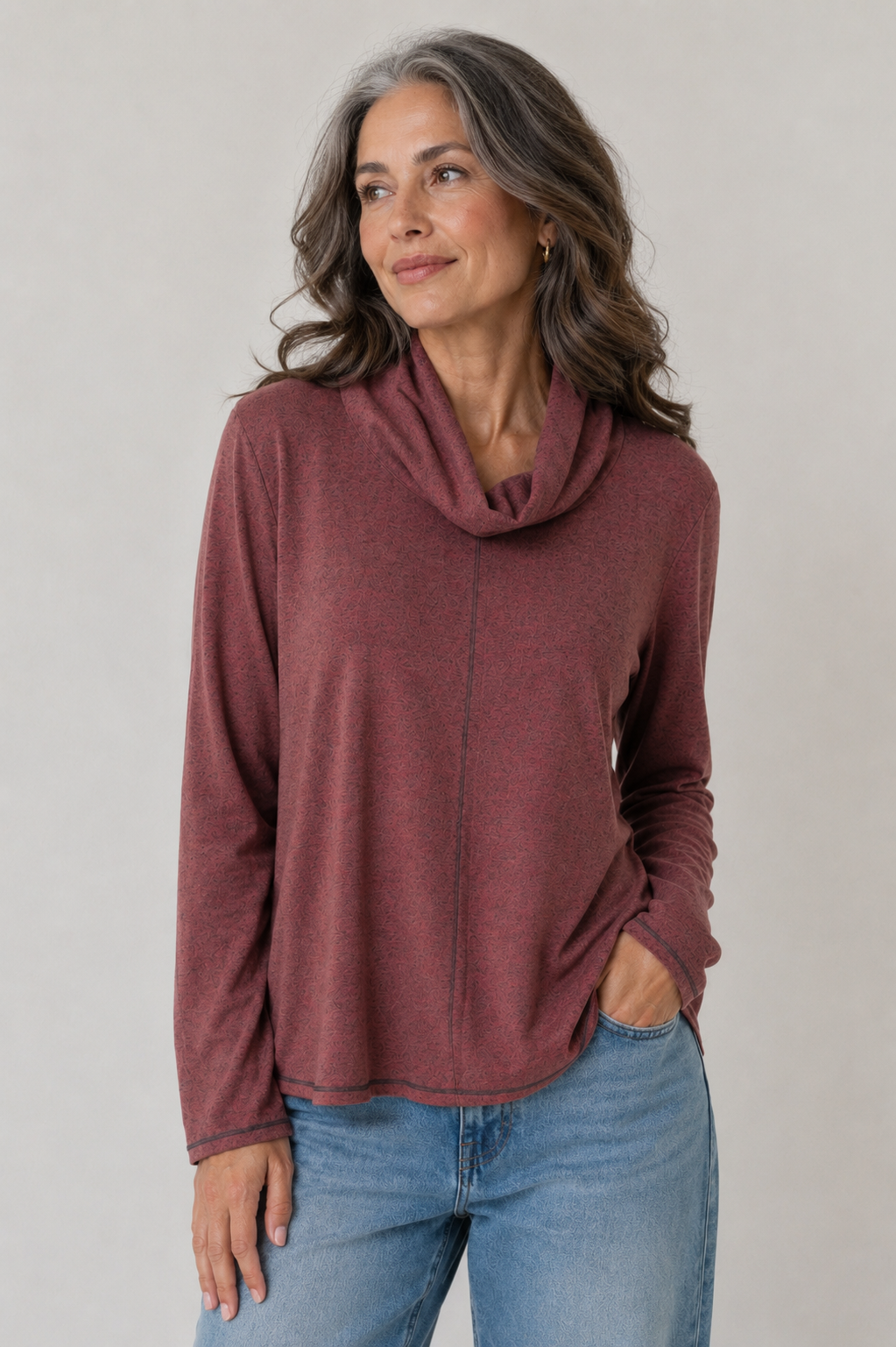 Woman wearing a maroon cowl-neck sweater and blue jeans against a plain background by vine Street